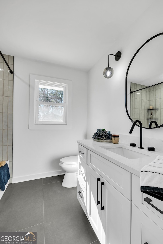 bathroom with toilet, a tile shower, and vanity