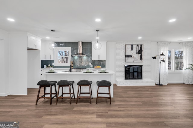 kitchen featuring white cabinetry, wall chimney exhaust hood, dark hardwood / wood-style flooring, and hanging light fixtures