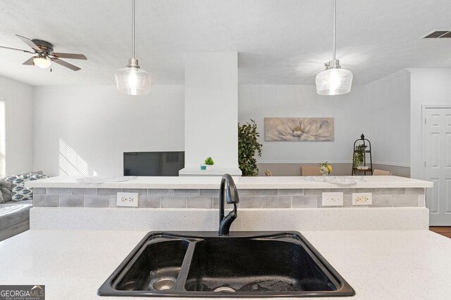 kitchen featuring sink, light hardwood / wood-style flooring, pendant lighting, a textured ceiling, and black appliances