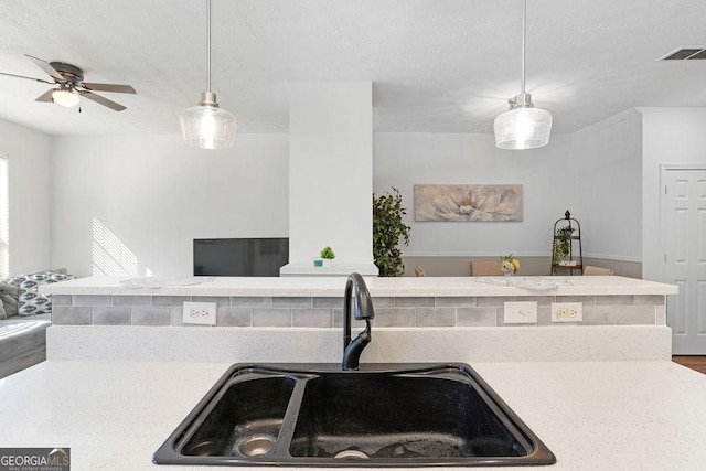 kitchen with pendant lighting, light countertops, visible vents, open floor plan, and a sink