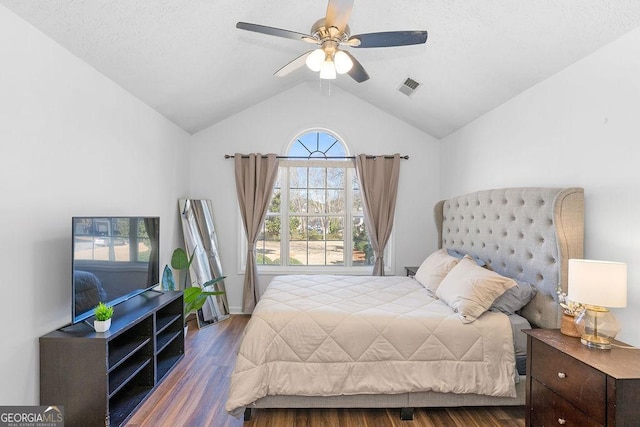 bedroom featuring lofted ceiling, dark wood-type flooring, visible vents, and a ceiling fan