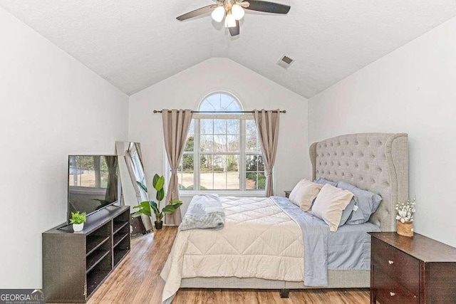 bedroom featuring a textured ceiling, light hardwood / wood-style floors, ceiling fan, and lofted ceiling