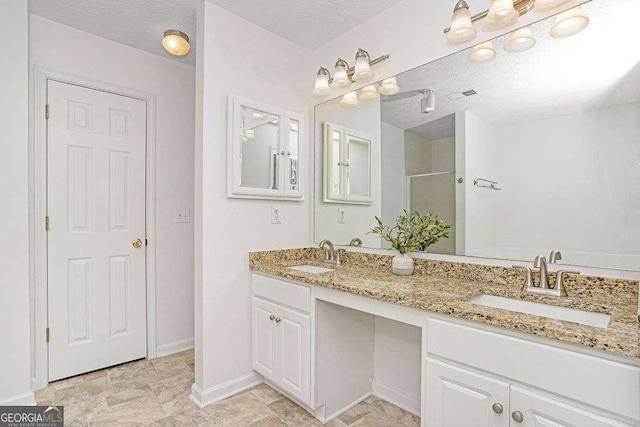 bathroom with a textured ceiling, an enclosed shower, a sink, and visible vents