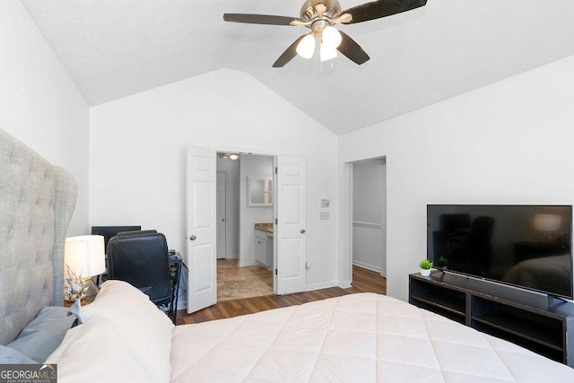 bedroom with a ceiling fan, lofted ceiling, connected bathroom, and wood finished floors