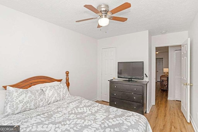 bedroom with ceiling fan, light hardwood / wood-style floors, and a textured ceiling