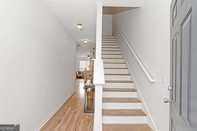 stairway with wood-type flooring and a textured ceiling