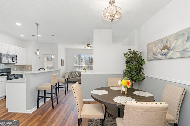 dining area with dark wood-style floors, recessed lighting, and ceiling fan with notable chandelier