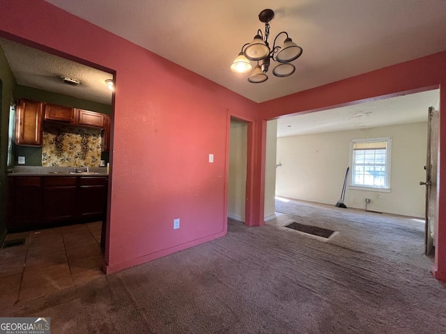 unfurnished dining area with dark carpet, sink, and an inviting chandelier