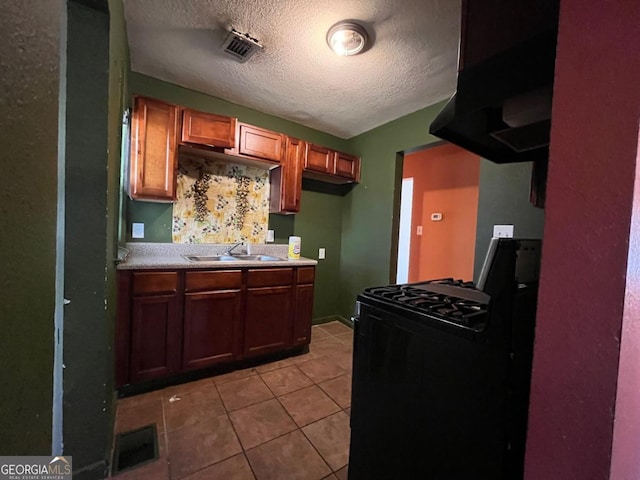 kitchen featuring light tile patterned floors, gas stove, a textured ceiling, and sink