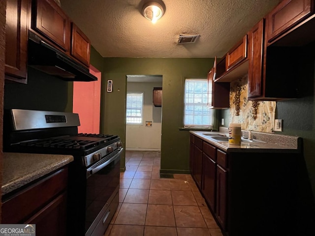 kitchen featuring stainless steel range with gas cooktop, light tile patterned flooring, and a textured ceiling