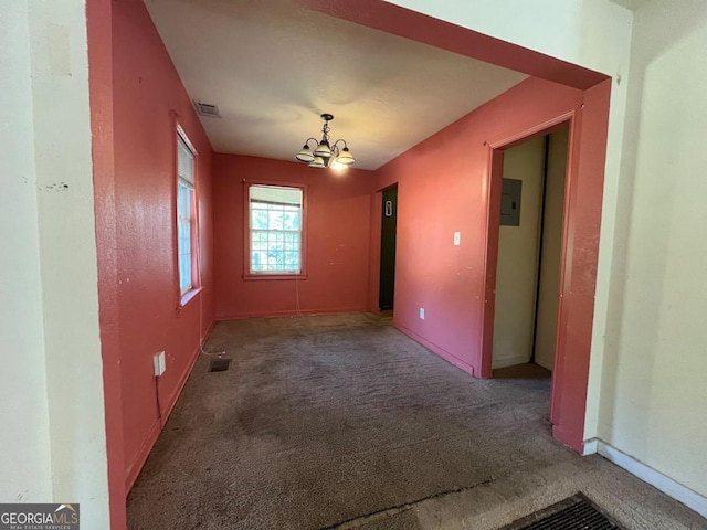 carpeted spare room featuring electric panel and an inviting chandelier