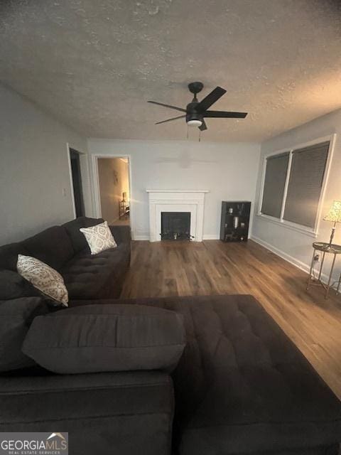 living room featuring hardwood / wood-style flooring, ceiling fan, and a textured ceiling