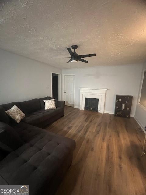 living room featuring ceiling fan, wood-type flooring, and a textured ceiling