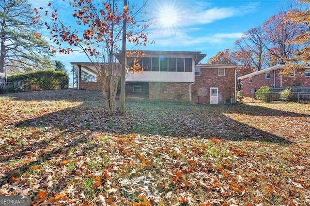 rear view of property featuring a lawn and a sunroom