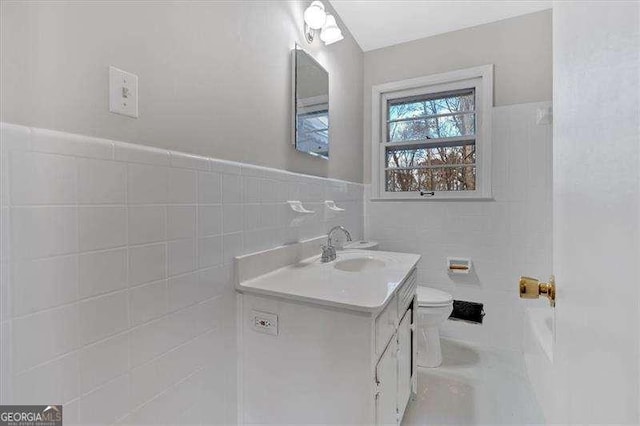 bathroom featuring vanity, tile walls, and toilet