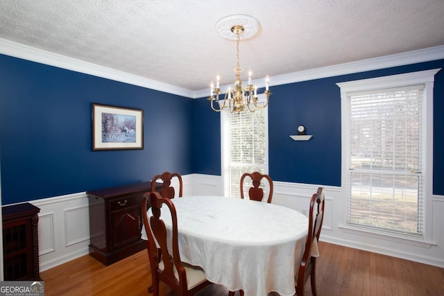 dining area with crown molding, hardwood / wood-style floors, a textured ceiling, and a notable chandelier