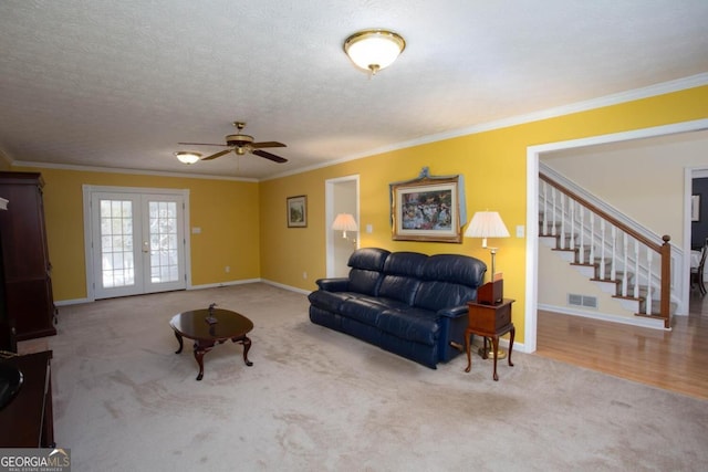 carpeted living room featuring ceiling fan, ornamental molding, french doors, and a textured ceiling