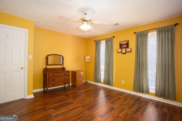 unfurnished room with dark wood-type flooring, ceiling fan, plenty of natural light, and a textured ceiling