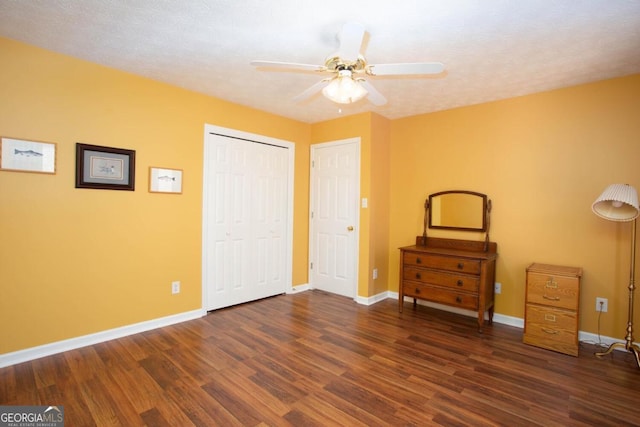 unfurnished bedroom featuring dark hardwood / wood-style flooring, a textured ceiling, a closet, and ceiling fan