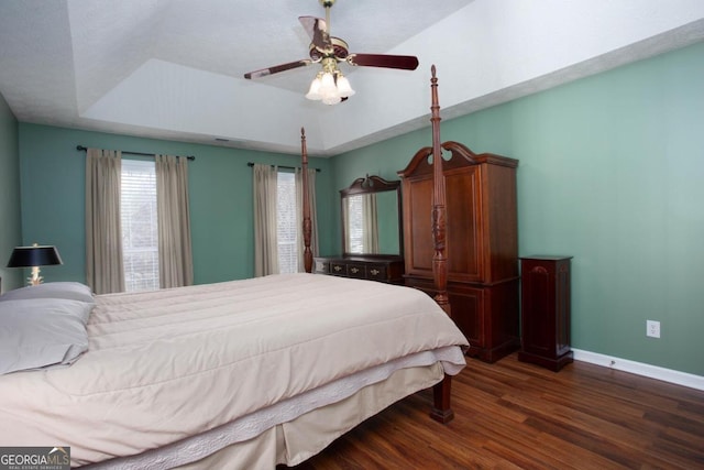 bedroom with ceiling fan, dark hardwood / wood-style floors, and a raised ceiling