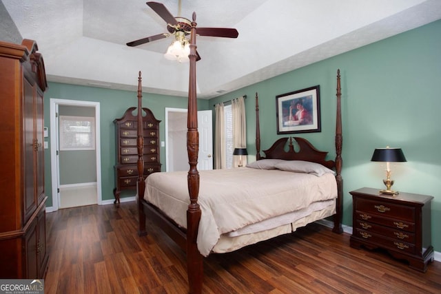 bedroom with dark hardwood / wood-style flooring, a textured ceiling, ceiling fan, and a tray ceiling