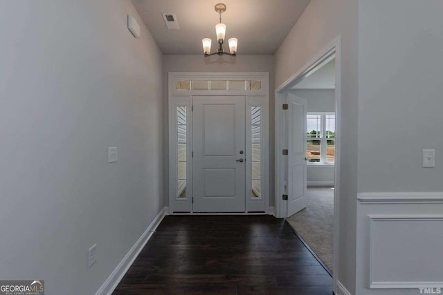 foyer entrance with dark hardwood / wood-style flooring and an inviting chandelier