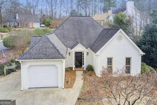 view of front facade with concrete driveway, a garage, brick siding, and a shingled roof