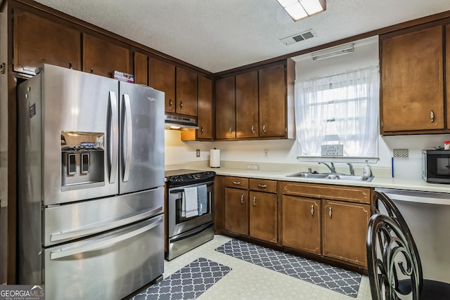 kitchen with a textured ceiling, sink, stainless steel appliances, and washer / clothes dryer