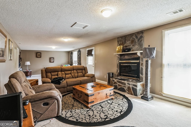 living room featuring a textured ceiling, a wealth of natural light, a fireplace, and light carpet