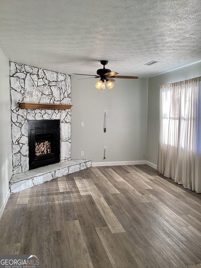 unfurnished living room with hardwood / wood-style floors, ceiling fan, a fireplace, and a textured ceiling