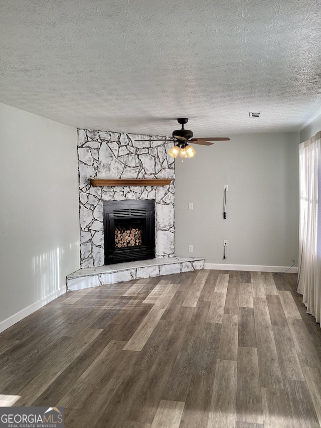 unfurnished living room with ceiling fan, a fireplace, hardwood / wood-style floors, and a textured ceiling