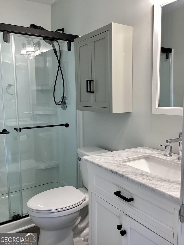 bathroom featuring an enclosed shower, vanity, and toilet