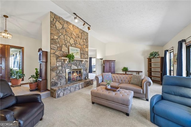 living room with rail lighting, a textured ceiling, vaulted ceiling, light carpet, and a fireplace