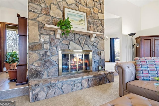 living room featuring carpet flooring, a healthy amount of sunlight, and a stone fireplace