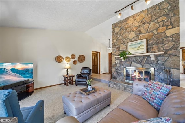 living room with a stone fireplace, light colored carpet, a textured ceiling, and track lighting