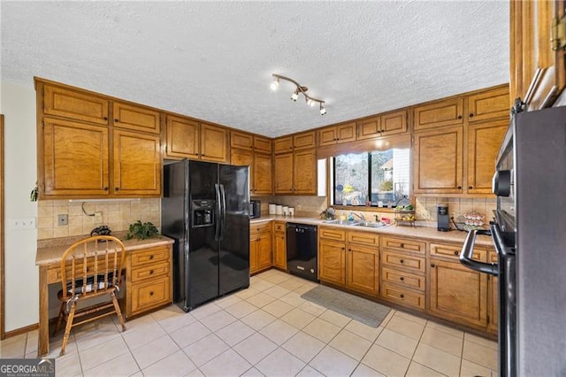 kitchen featuring sink, backsplash, a textured ceiling, light tile patterned flooring, and black appliances