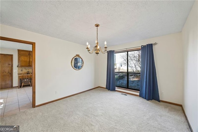 carpeted empty room featuring a textured ceiling and a notable chandelier