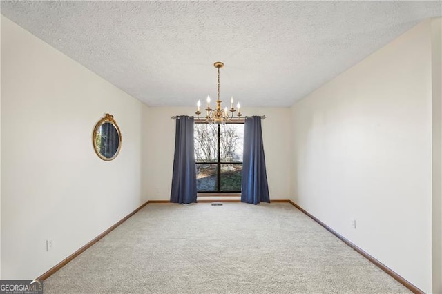 empty room with a textured ceiling, carpet floors, and a notable chandelier