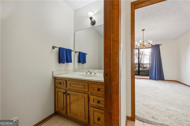 bathroom with a chandelier, a textured ceiling, vanity, and tile patterned flooring