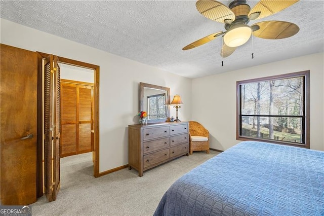 bedroom with ceiling fan, a closet, light colored carpet, and a textured ceiling