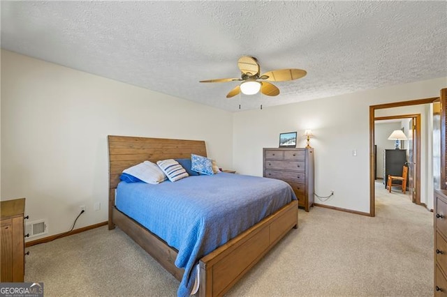 bedroom with a textured ceiling, ceiling fan, and light carpet