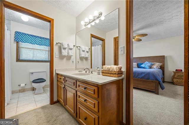 bathroom with vanity, tile patterned flooring, ceiling fan, toilet, and a textured ceiling