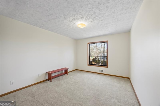 unfurnished room with a textured ceiling and light colored carpet