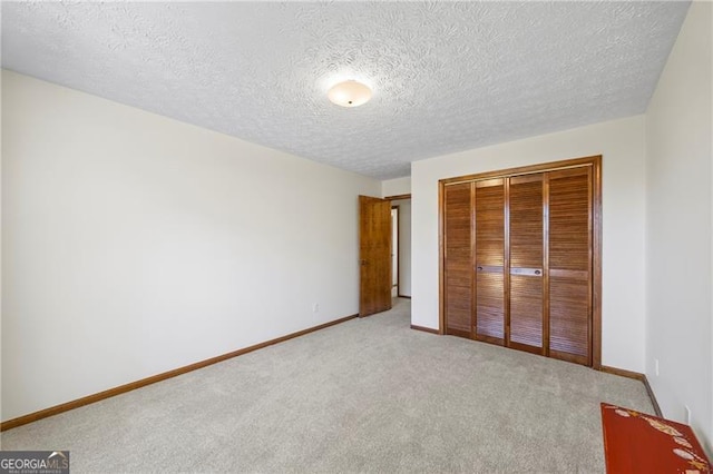 unfurnished bedroom featuring light carpet, a closet, and a textured ceiling