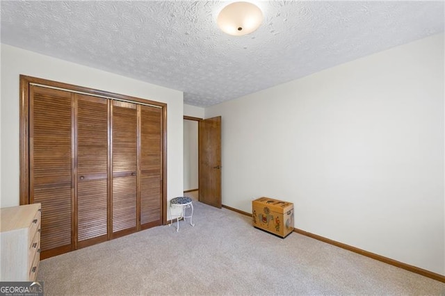 unfurnished bedroom with a closet, light colored carpet, and a textured ceiling