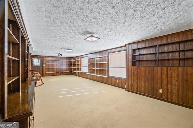 interior space with a textured ceiling, concrete floors, and wooden walls