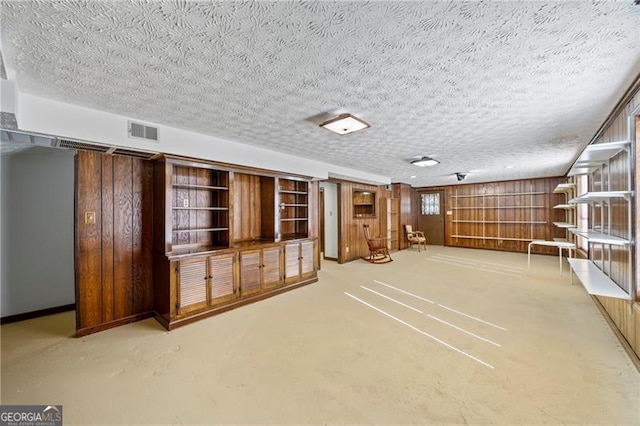 unfurnished living room with wood walls, concrete floors, and a textured ceiling