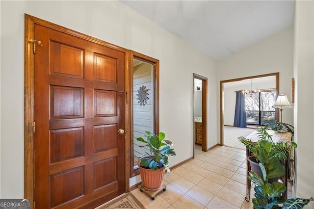 foyer with a chandelier, light tile patterned flooring, and vaulted ceiling