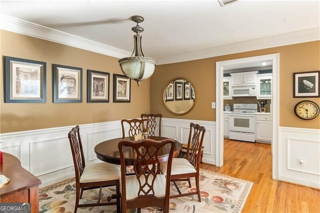 dining room with light wood-type flooring and crown molding