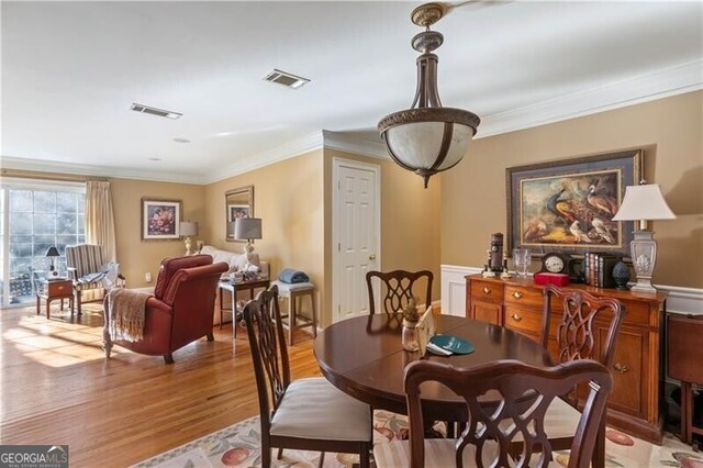 dining area with light wood-type flooring and crown molding